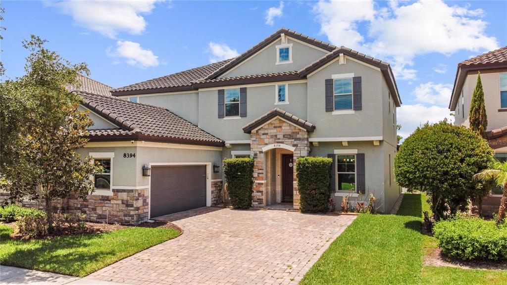 A two-story suburban house features a stone-accented entryway, a paved driveway, and a garage — 8394 LOOKOUT POINTE DRIVE, WINDERMERE, FL