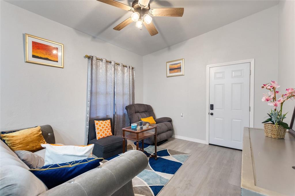 A living room features a grey sofa, a recliner, a patterned rug, and a white door — 1495 PENNIWA STREET, INTERCESSION CITY, FL