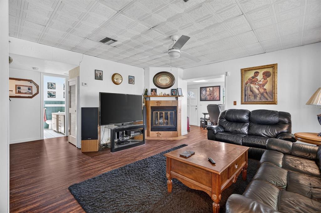 A living room features a corner fireplace, a black leather sofa, and wood-look flooring — 1865 CEDARWOOD DRIVE, MELBOURNE, FL