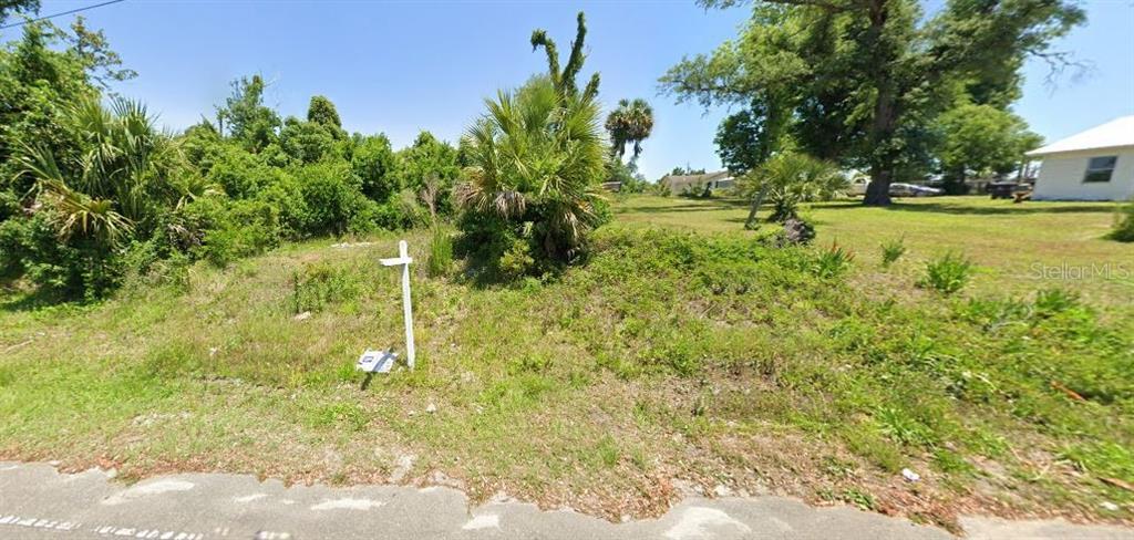 A vacant, grassy lot with scattered trees and shrubs sits along a paved road — 135 EVERITT AVENUE, PANAMA CITY, FL