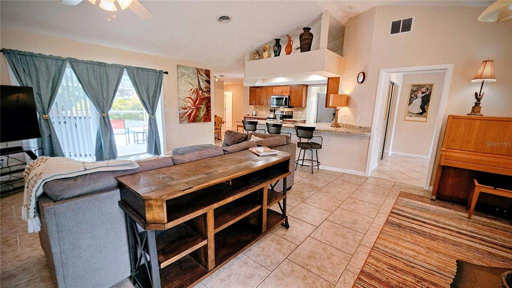 A living room with a sofa, console table, kitchen breakfast bar, and tile flooring — 881 BAYSHORE DRIVE, ENGLEWOOD, FL