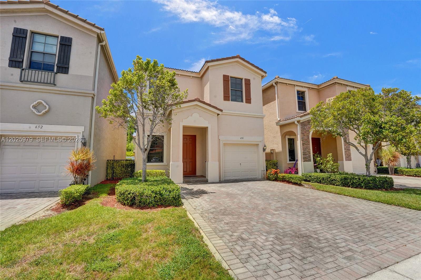 A two-story beige house with a brick driveway and a single-car garage — 650 NE 191st Ter, Miami FL 33179, MIAMI, FL