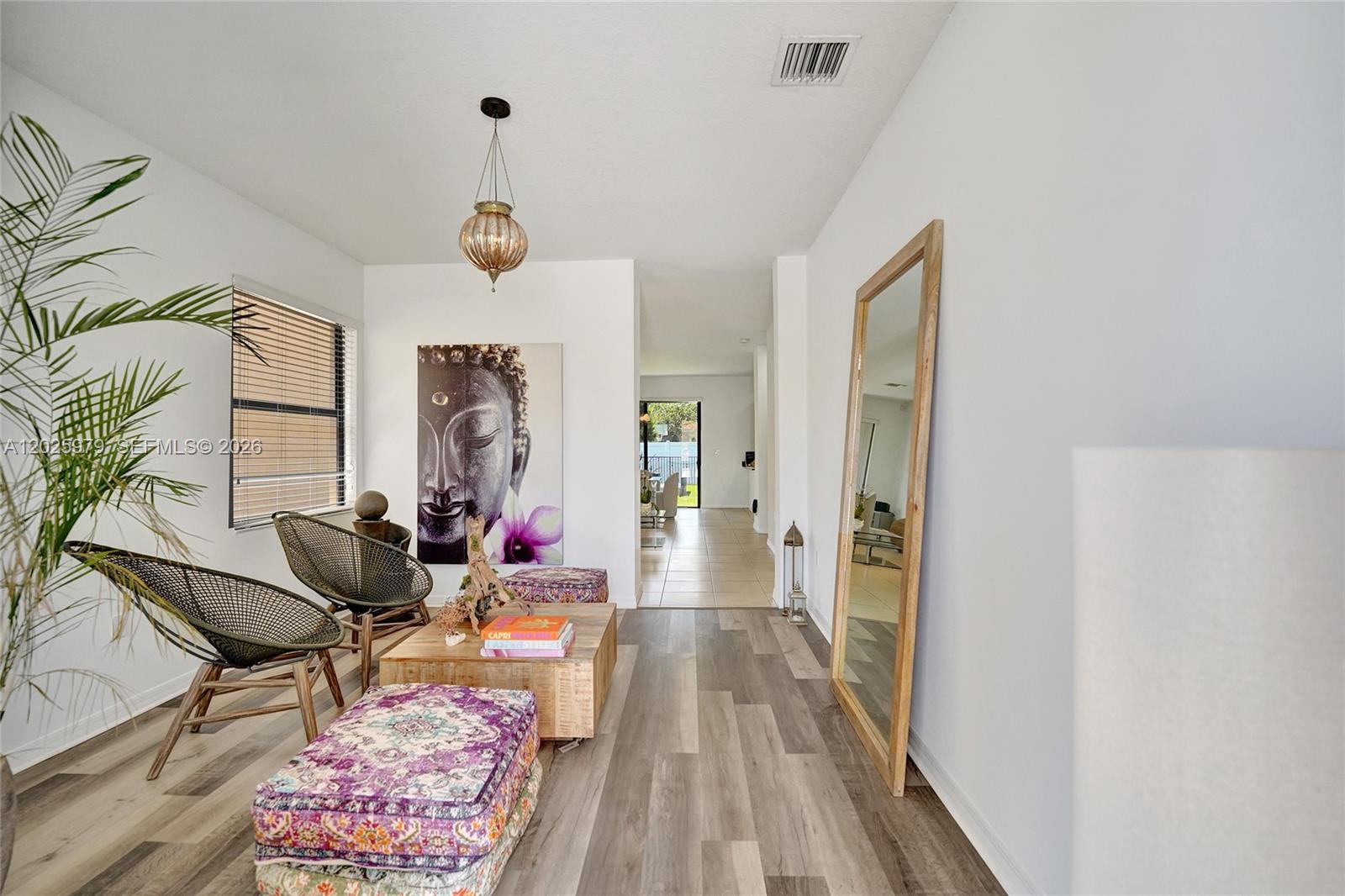 A living area features wood-look flooring, two woven chairs, a coffee table, and a large mirror — 650 NE 191st Ter, Miami FL 33179, MIAMI, FL