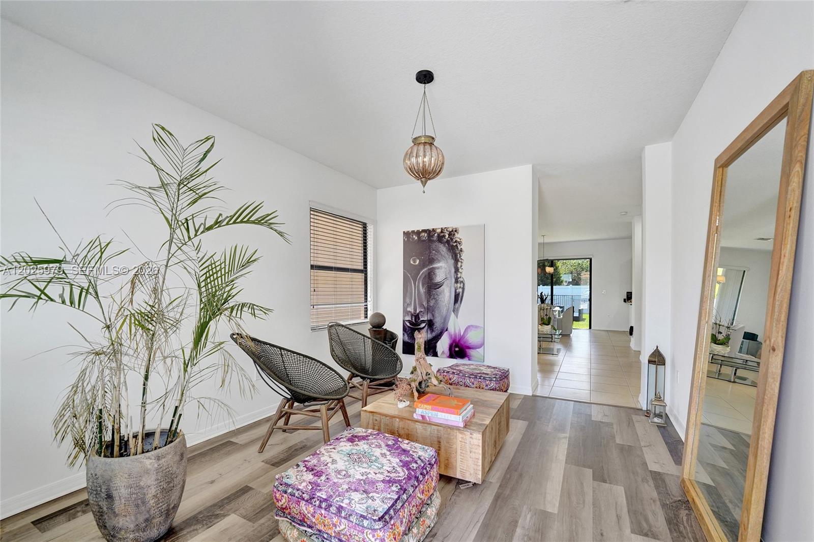 A living area features wood-look flooring, two woven chairs, a wooden coffee table, and Buddha art — 650 NE 191st Ter, Miami FL 33179, MIAMI, FL