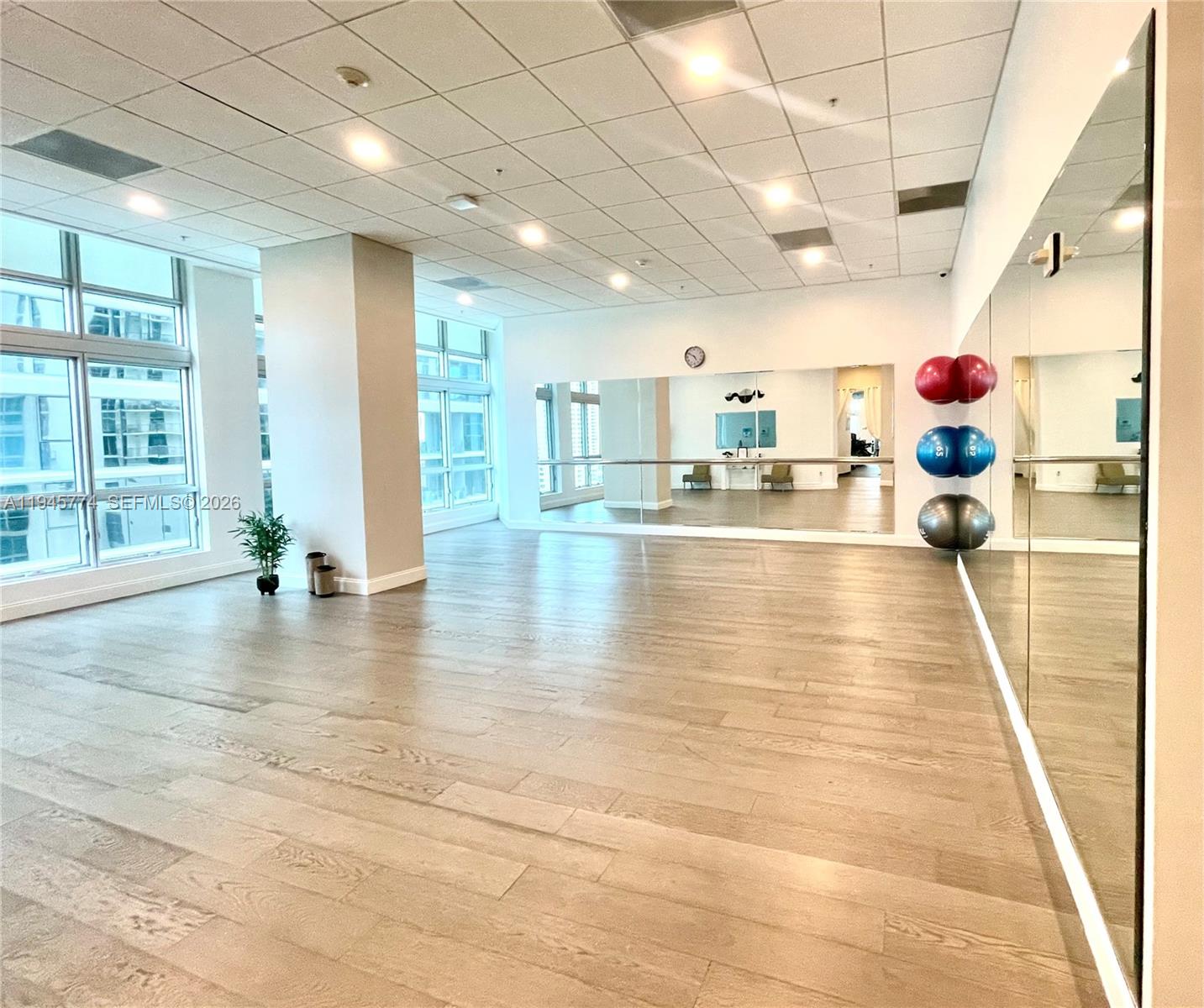 This fitness studio features light wood flooring, a mirrored wall, and large windows — 300 S Biscayne Blvd # 1803, Miami FL 33131, MIAMI, FL