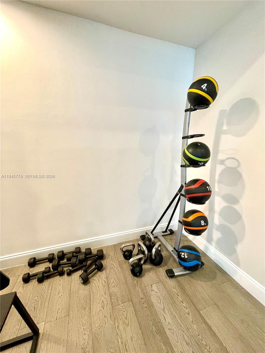 A home gym area features a medicine ball rack and various dumbbells on a wood floor — 300 S Biscayne Blvd # 1803, Miami FL 33131, MIAMI, FL