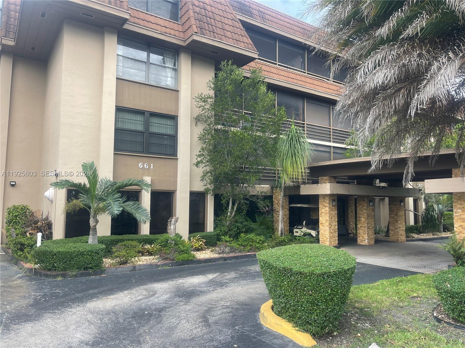 A multi-story apartment building features a brown mansard roof and a covered stone entryway — 661 NE 195th St # 309, Miami FL 33179, MIAMI, FL