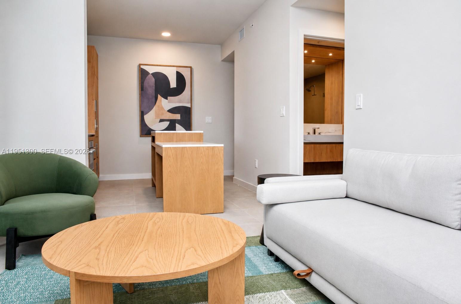 A modern kitchen features light wood cabinetry, white countertops, and an island with stools — 11 NE 6th St # 1109, Miami FL 33132, MIAMI, FL