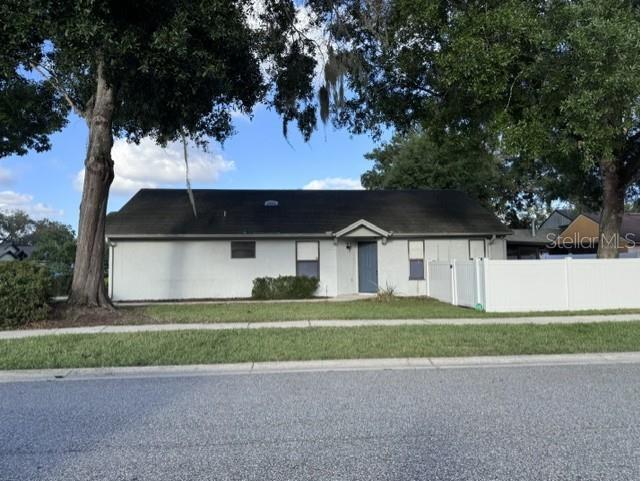 A single-story house with a white exterior and a dark roof sits behind a fence — 1214 CREEKBOTTOM CIRCLE, ORLANDO, FL