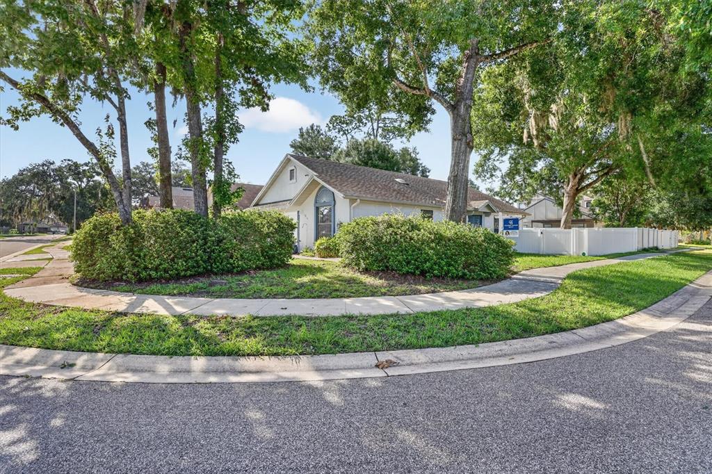A single-story house with a tan exterior sits on a corner lot with mature trees — 1214 CREEKBOTTOM CIRCLE, ORLANDO, FL