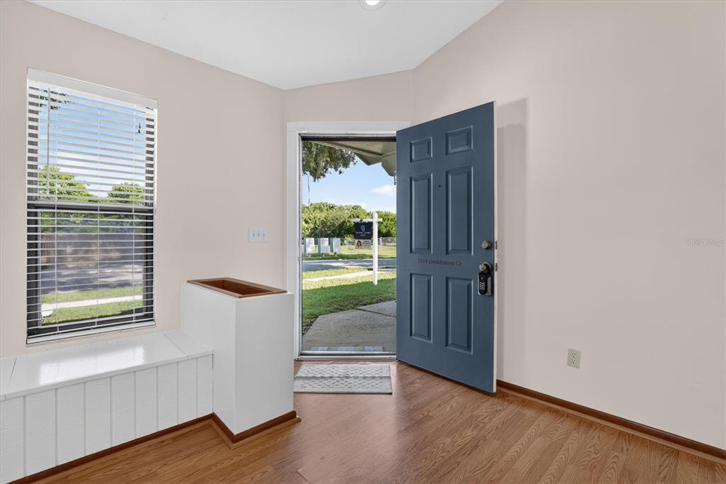 An entryway features wood flooring, a blue front door, and a built-in white bench — 1214 CREEKBOTTOM CIRCLE, ORLANDO, FL