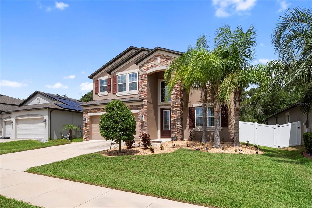 A two-story house with a stone facade, brown trim, and a palm-lined front yard — 11438 ACACIA GROVE LANE, RIVERVIEW, FL