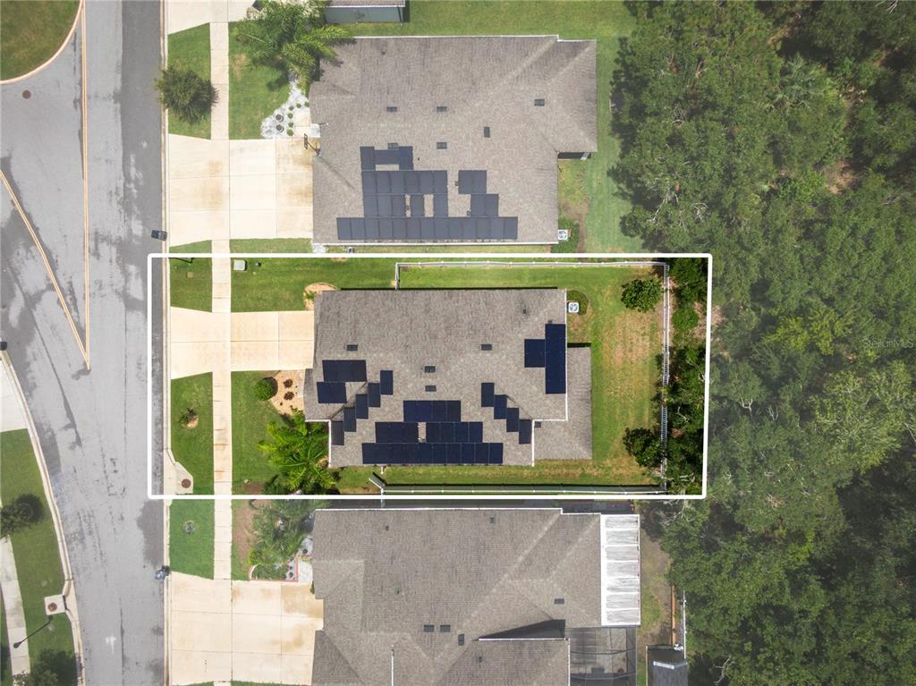 An aerial view shows a residential house with solar panels on its roof and a backyard — 11438 ACACIA GROVE LANE, RIVERVIEW, FL