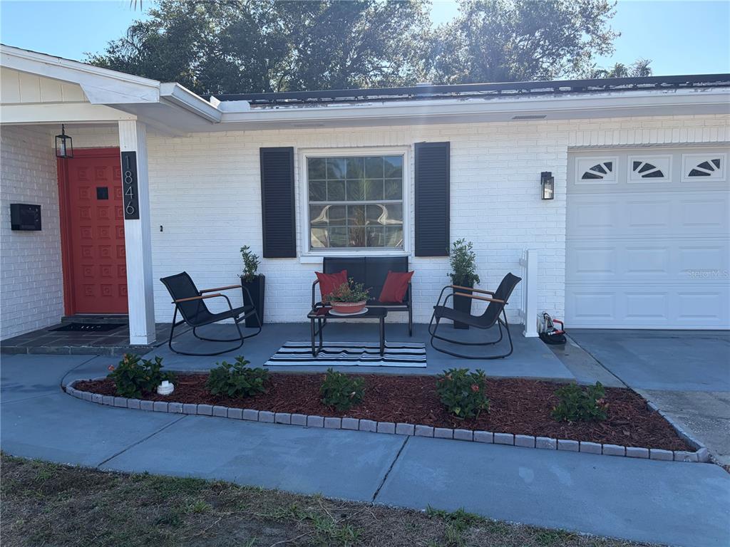 A white brick house exterior features a red front door, a porch, and a garage — 1846 ELMHURST DRIVE, CLEARWATER, FL
