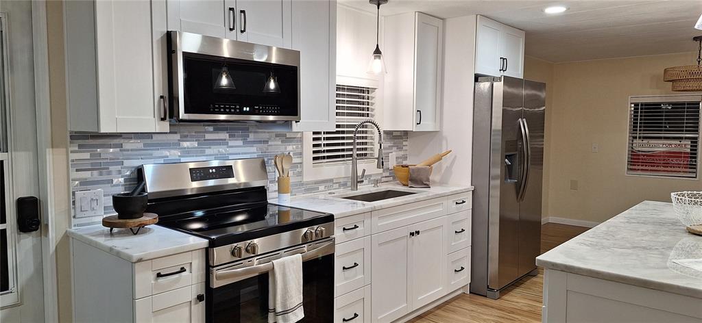 A kitchen features white cabinets, stainless steel appliances, and a marble-patterned countertop — 50 DOGWOOD COURT UNIT 11, SAFETY HARBOR, FL