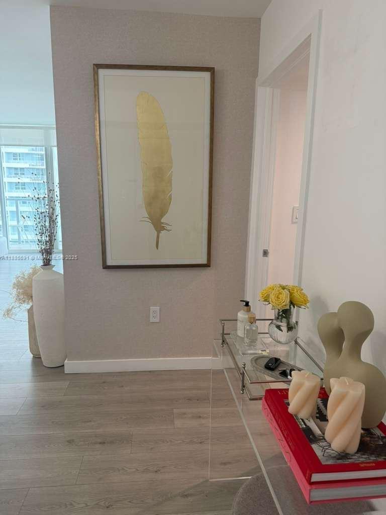 A hallway features light wood flooring, a gold feather wall art piece, and a glass console — 1155 Brickell Bay Dr # 1408, Miami FL 33131, MIAMI, FL