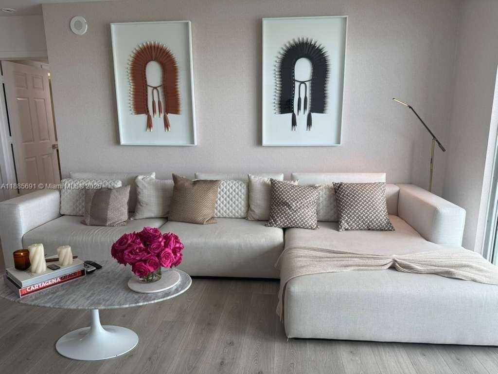 A modern living room features a large white sectional sofa, a marble coffee table, and two framed wall art pieces — 1155 Brickell Bay Dr # 1408, Miami FL 33131, MIAMI, FL