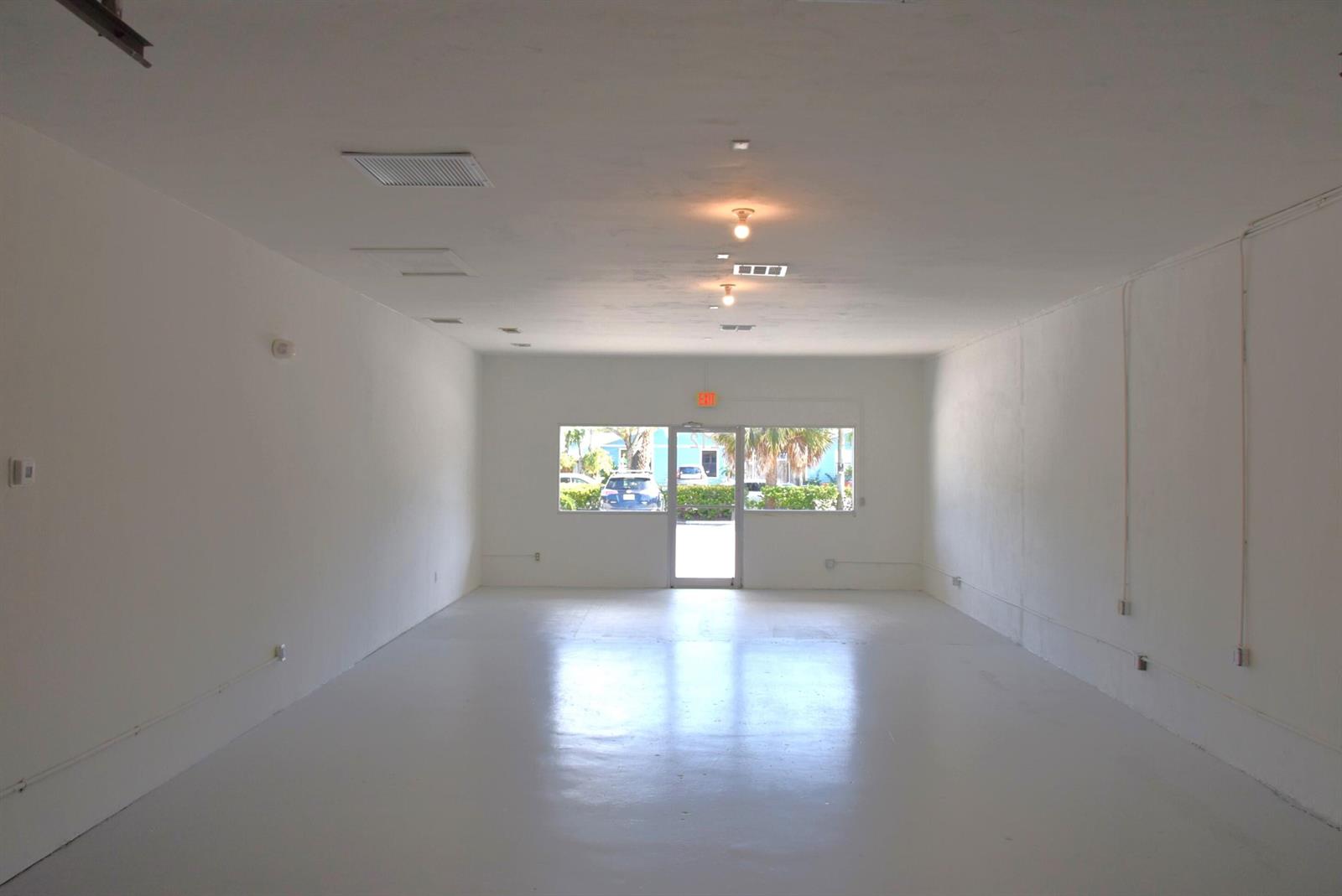 An empty, white-walled commercial space with a glossy floor and a glass entrance door — 200 Hibiscus Street # 212, Jupiter FL 33458, JUPITER, FL