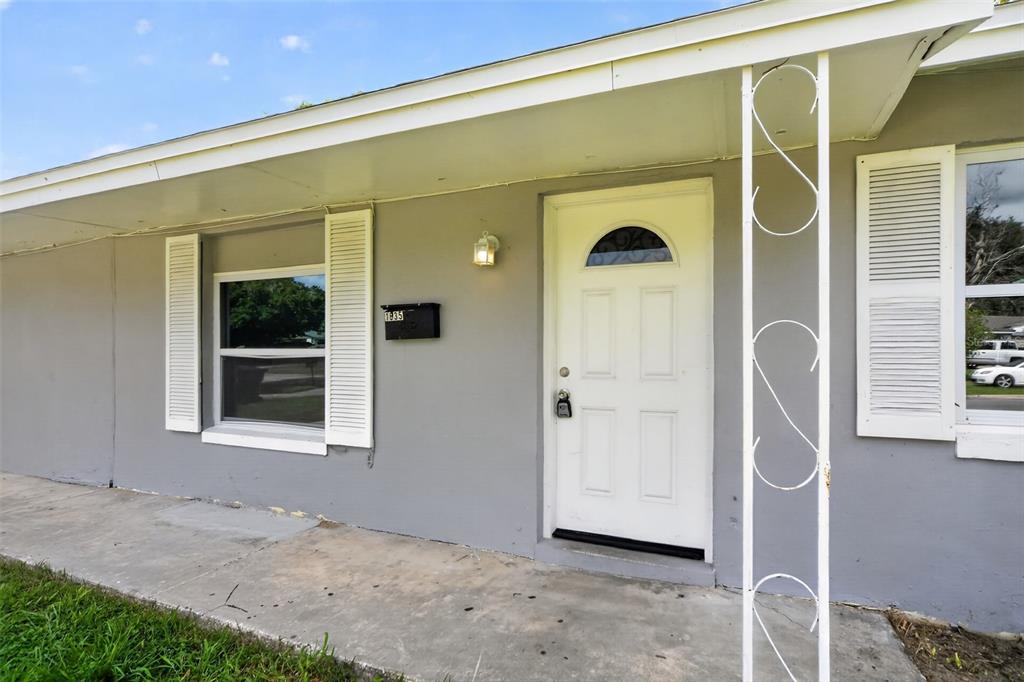 A gray house exterior features a white front door, white shutters, and a metal porch support — 1635 RAVENALL AVENUE, ORLANDO, FL