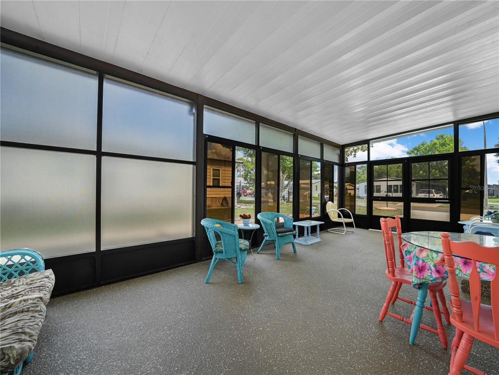 A screened-in porch features a textured floor, white ceiling, and multiple windows with outdoor views — 124 KENSINGTON PARK DRIVE, DAVENPORT, FL