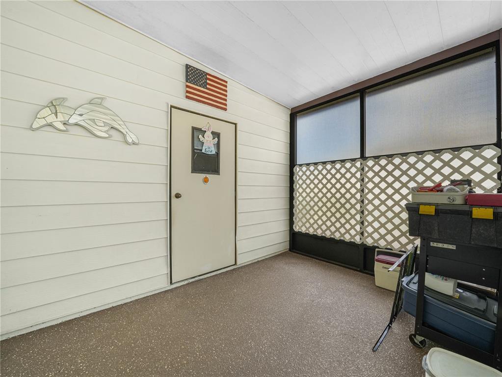 A covered porch features light-colored siding, a door with a small sign, and screened walls — 124 KENSINGTON PARK DRIVE, DAVENPORT, FL