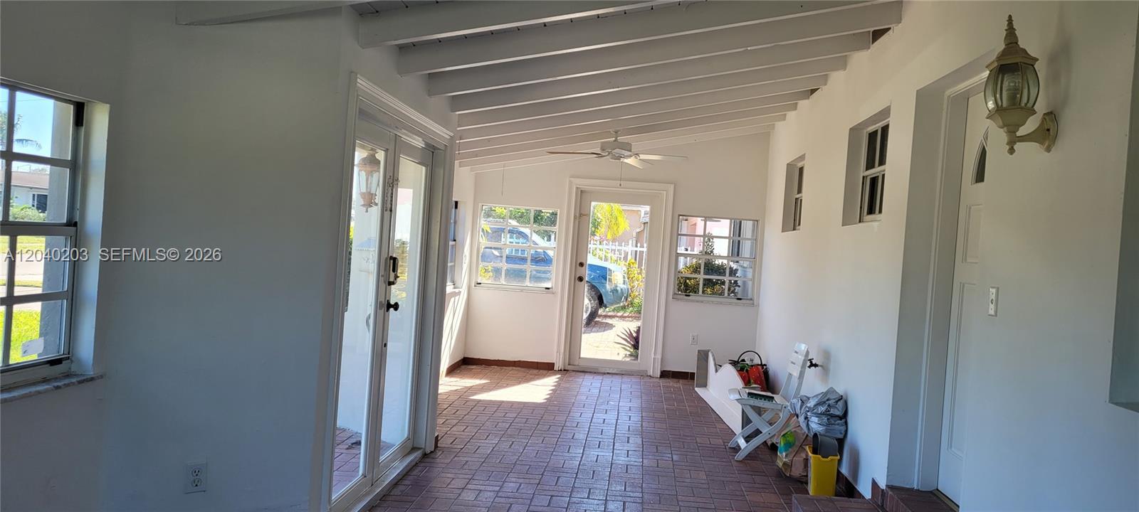 A sunroom features a brick floor, white exposed beams, and multiple windows and doors — 5200 SW 89th Pl, Miami FL 33165, MIAMI, FL