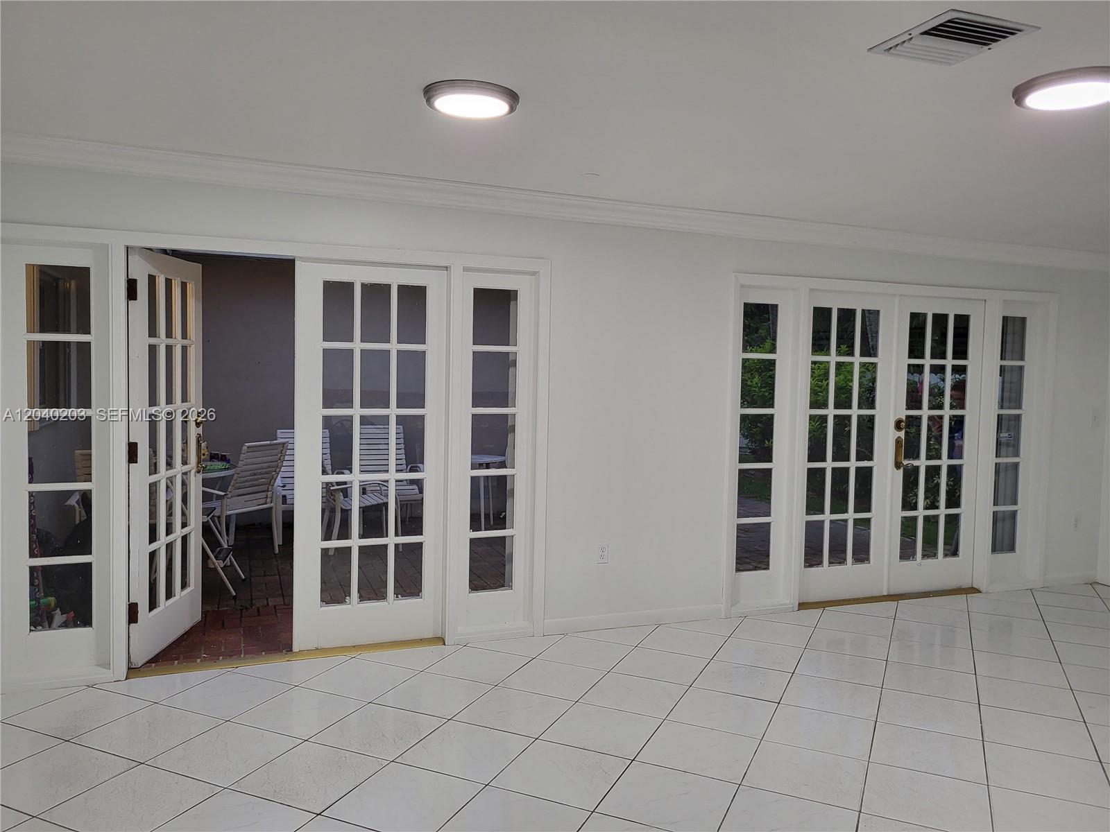 A bright room features white tiled floors, recessed lighting, and multiple sets of French doors — 5200 SW 89th Pl, Miami FL 33165, MIAMI, FL
