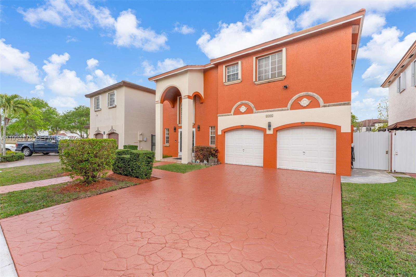 A two-story orange house features a stamped concrete driveway, two garage doors, and an arched entryway — 6502 SW 157th Ct, Miami FL 33193, MIAMI, FL