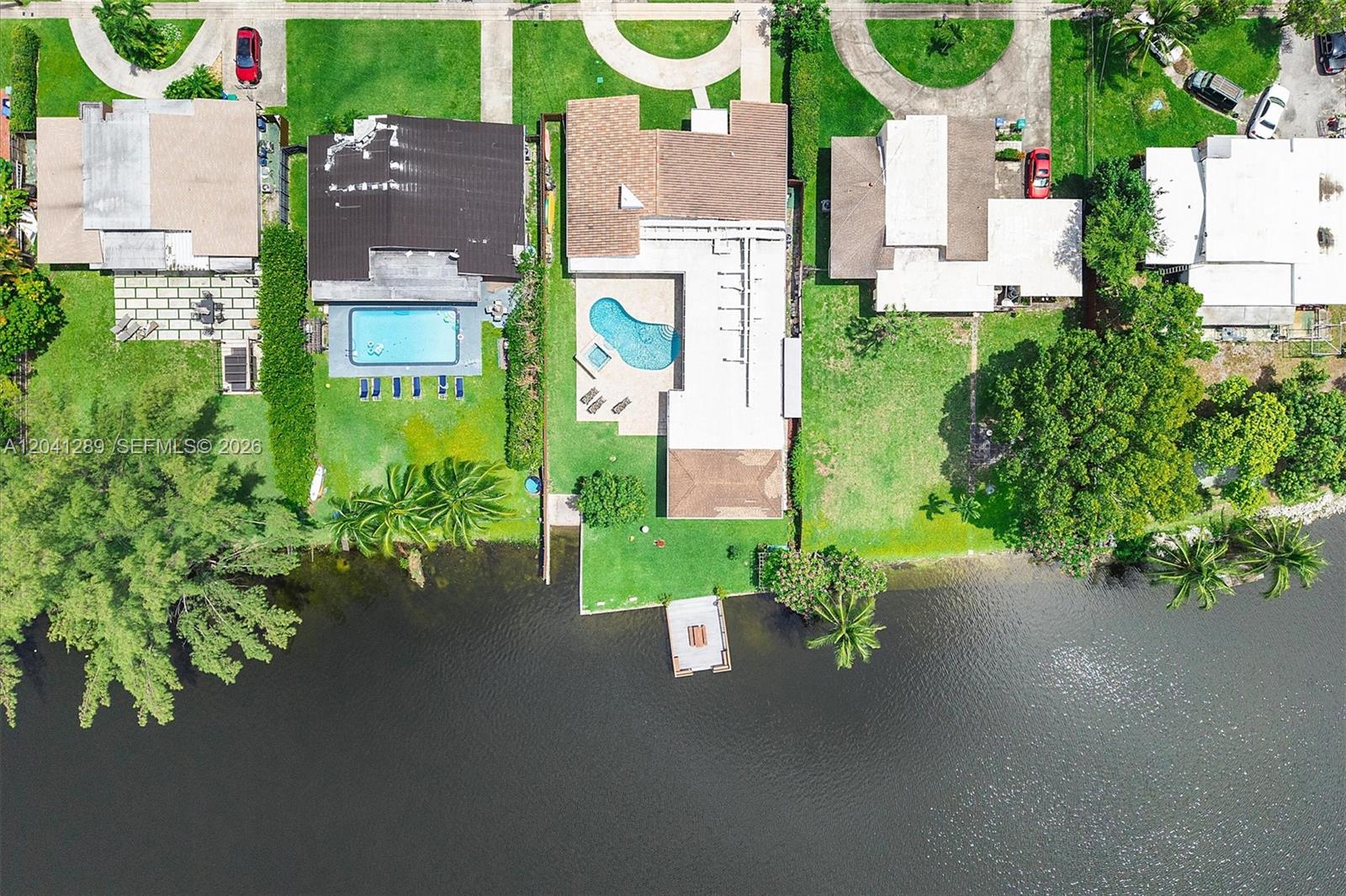 An aerial view shows three waterfront houses with pools, lawns, and docks along a canal — 2531 NE 195th St, Miami FL 33180, MIAMI, FL