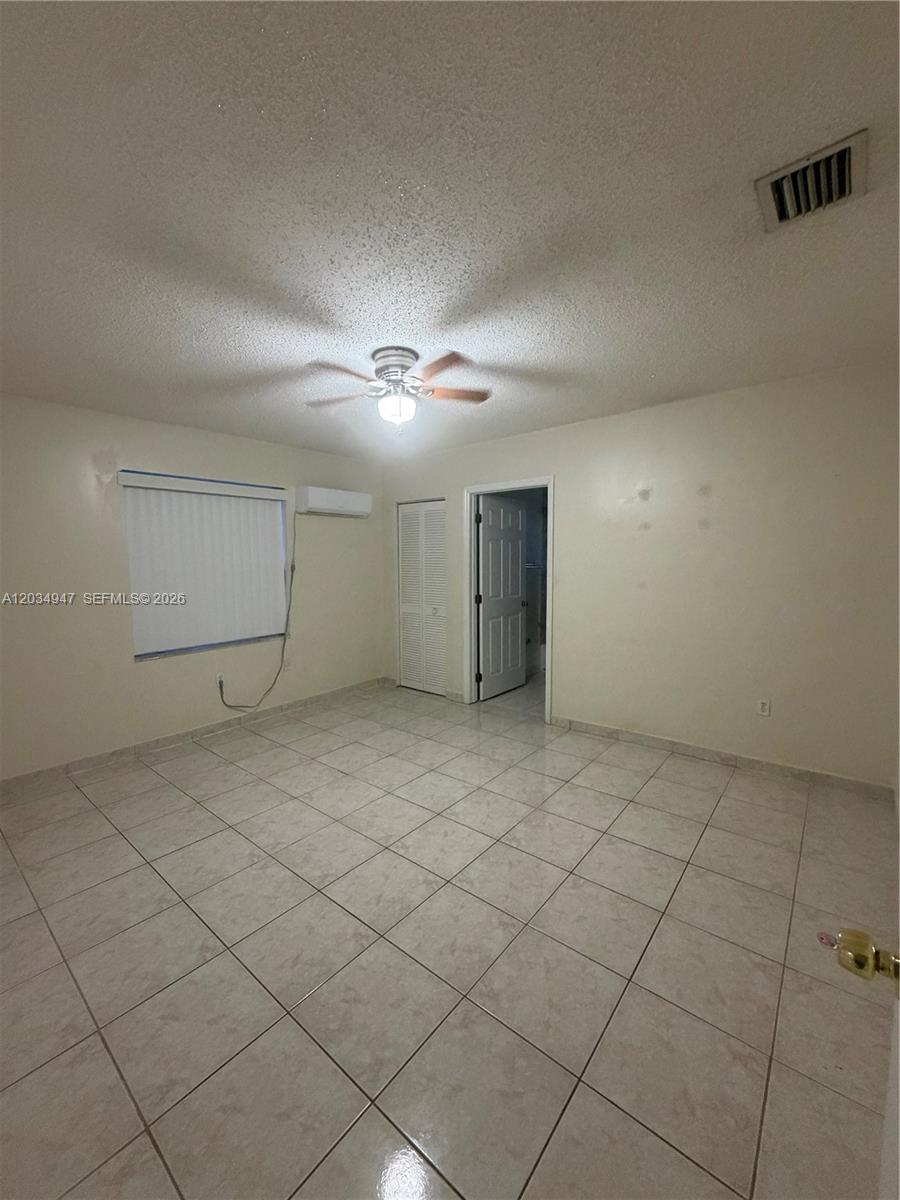 A bedroom features beige tile flooring, a ceiling fan, and a wall-mounted air conditioning unit — 15431 SW 101st Ave, Miami FL 33157, MIAMI, FL