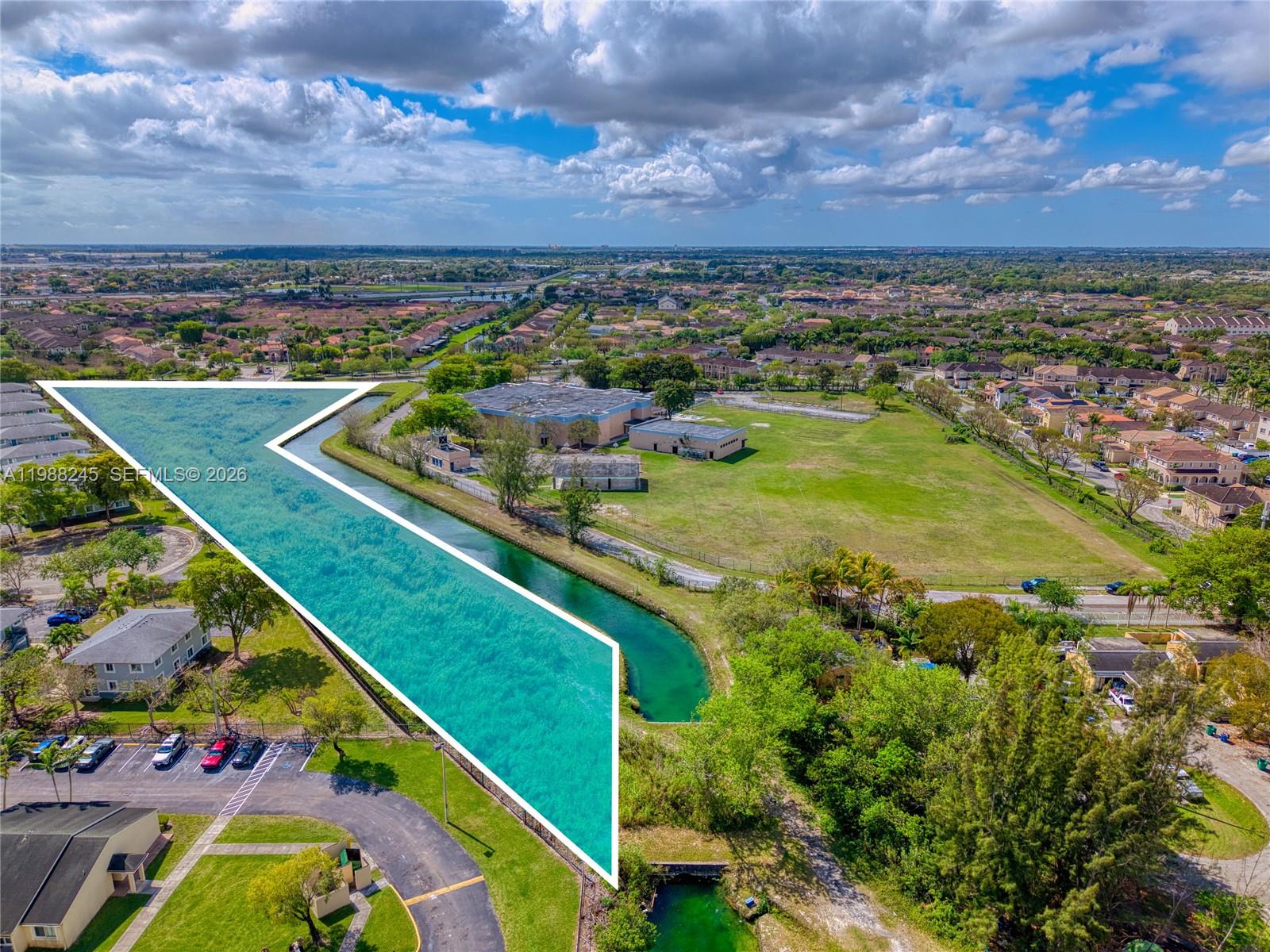 An aerial view shows a large, grassy lot bordered by a canal and residential buildings — SW 272 ST, Miami FL 33032, MIAMI, FL