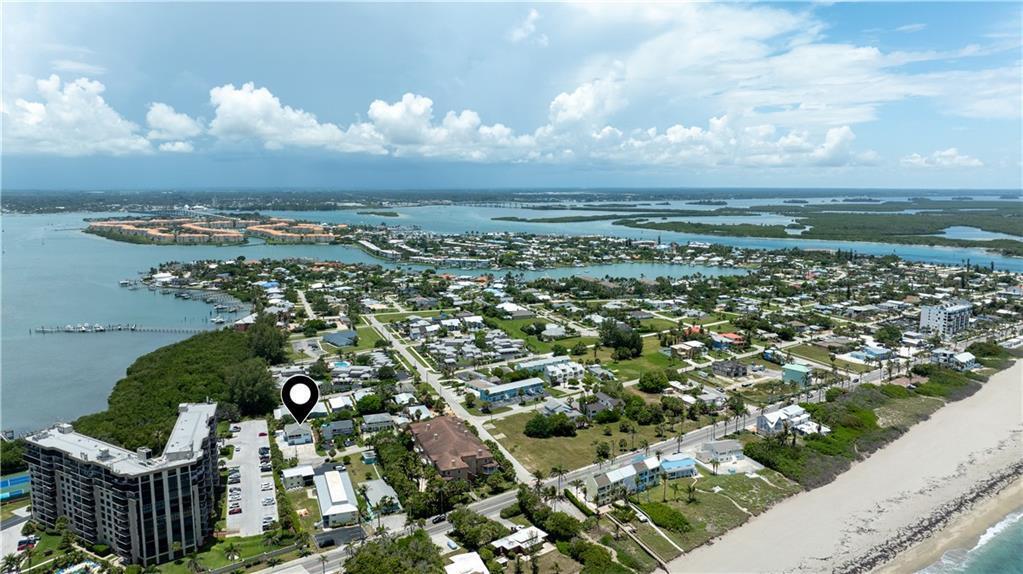An aerial view shows a coastal neighborhood with a marked property near the beach — HUTCHINSON ISLAND, FL