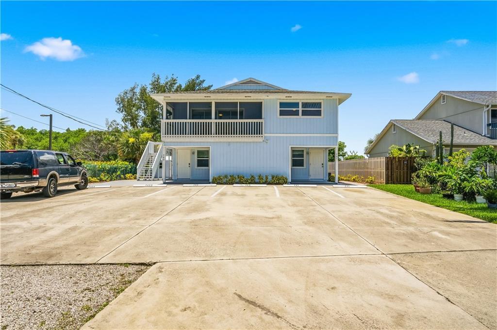 A two-story light blue building with a screened balcony and a paved parking lot — HUTCHINSON ISLAND, FL