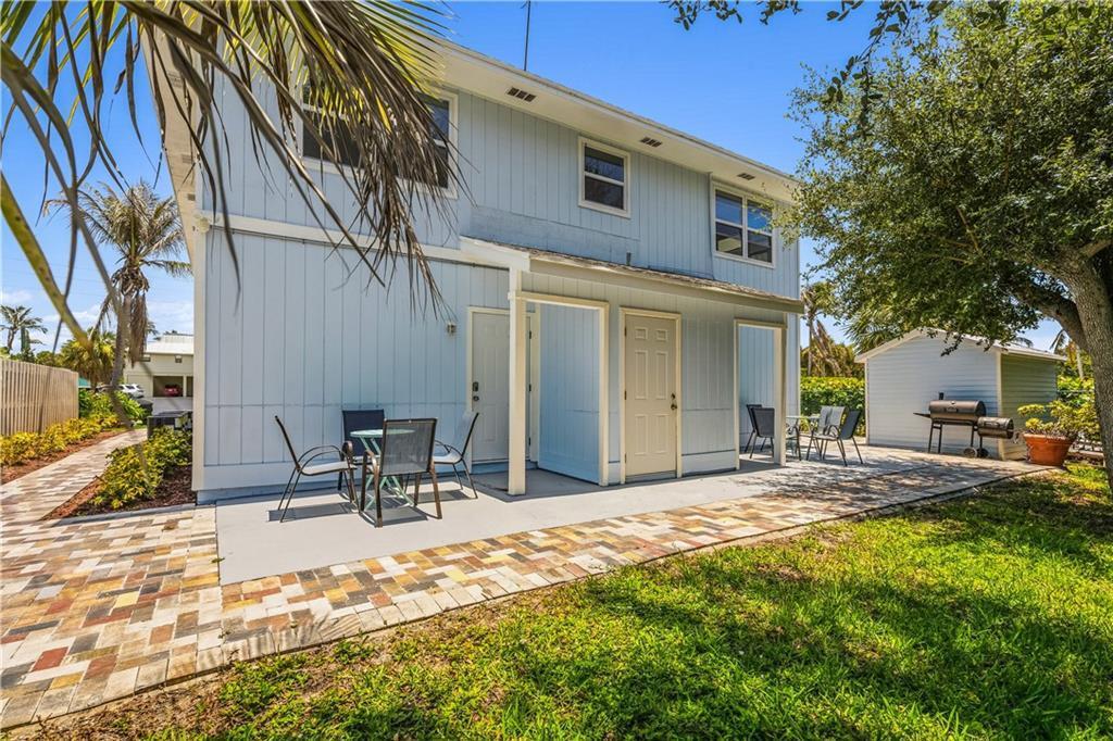 The exterior of a light blue two-story house features a paved patio and outdoor furniture — HUTCHINSON ISLAND, FL