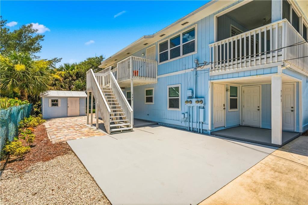 A two-story light blue house with an exterior staircase, a patio, and a small shed — HUTCHINSON ISLAND, FL