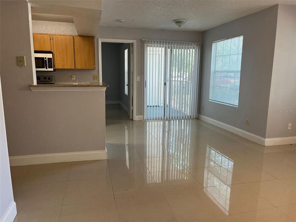 An open-concept dining area features light-colored tile flooring, a kitchen pass-through, and sliding glass doors — 11526 WESTWOOD BOULEVARD UNIT 717, ORLANDO, FL