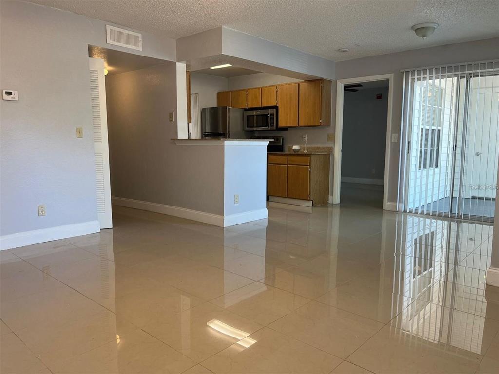 An open-concept living room with tile flooring leads to a kitchen with wood cabinets — 11526 WESTWOOD BOULEVARD UNIT 717, ORLANDO, FL