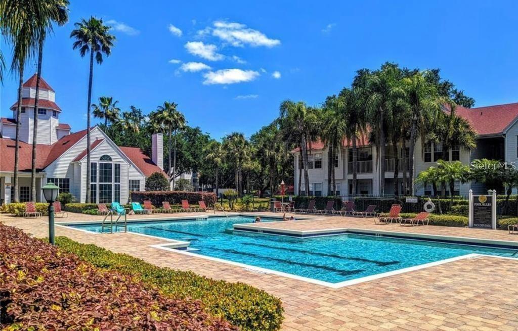 A swimming pool with lounge chairs sits in front of a multi-story residential building — 11526 WESTWOOD BOULEVARD UNIT 717, ORLANDO, FL