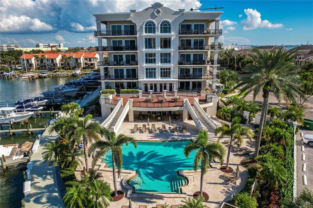 An aerial view of a multi-story waterfront condominium building with a pool and boat slips — 202 WINDWARD PASSAGE UNIT 603, CLEARWATER BEACH, FL