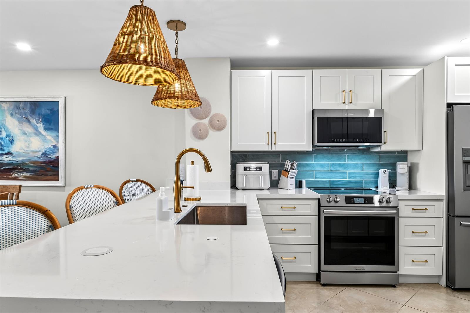 A modern kitchen features white cabinets, a blue tile backsplash, and a large island — 111 N Pompano Beach Boulevard # 611, Pompano Beach FL 33062, POMPANO BEACH, FL