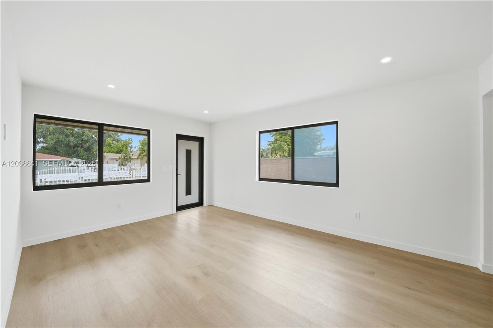 A bright, empty room features white walls, light wood-look flooring, and two black-framed windows — 1861 NW 27th St # 1, Miami FL 33142, MIAMI, FL