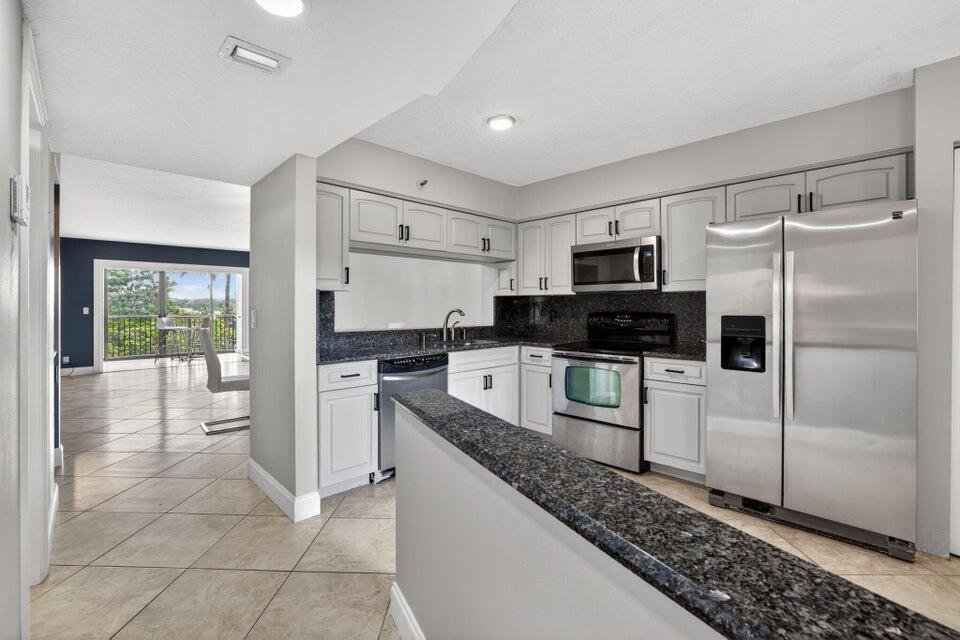 A kitchen with white cabinets, granite countertops, stainless steel appliances, and tile flooring — 2206 S Cypress Bend Drive # 401, Pompano Beach FL 33069, POMPANO BEACH, FL