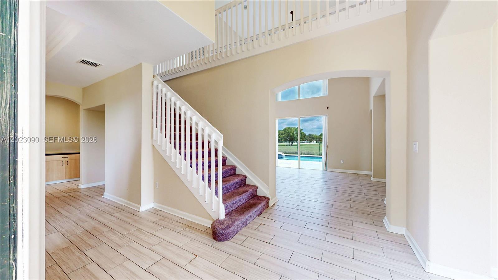 An entryway features light tile flooring, a carpeted staircase with white railings, and a pool view — 1730 SE 20th Ter, Homestead FL 33035, HOMESTEAD, FL