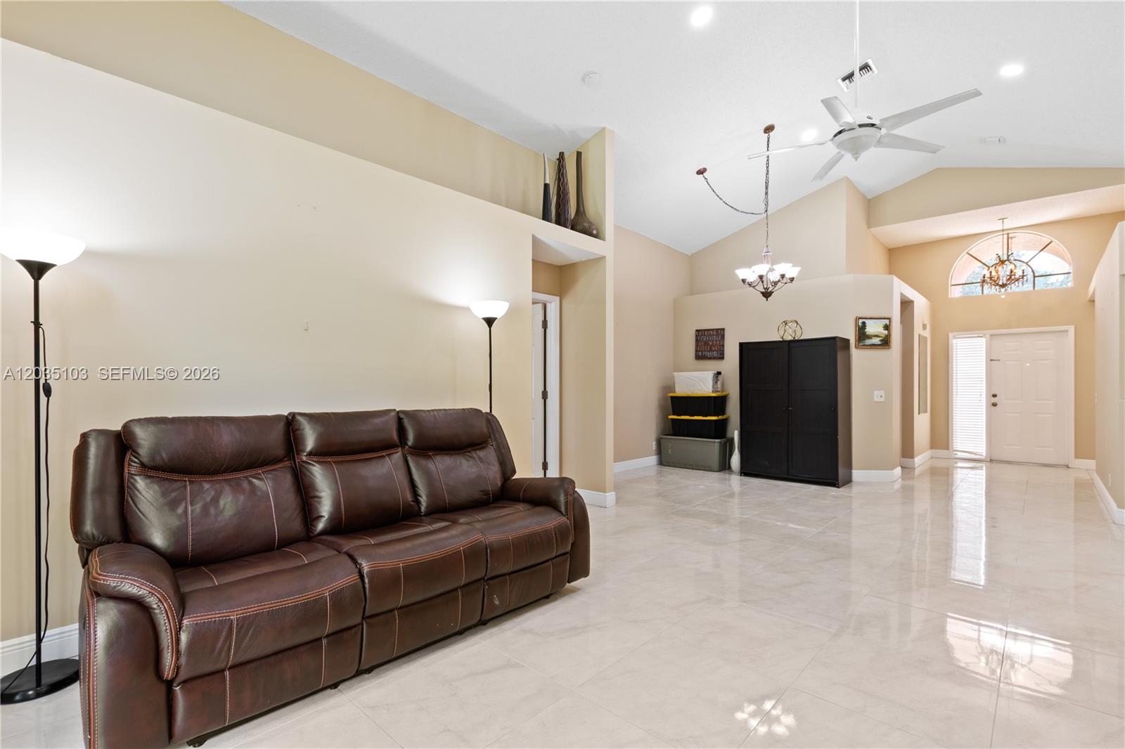 A living room features a brown leather sofa, tile flooring, and high vaulted ceilings — 11637 NW 3rd Dr, Coral Springs FL 33071, CORAL SPRINGS, FL