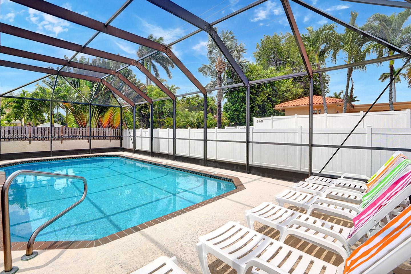 A swimming pool is enclosed by a screened lanai with lounge chairs on the deck — 947 Washington St, Hollywood FL 33019, HOLLYWOOD, FL