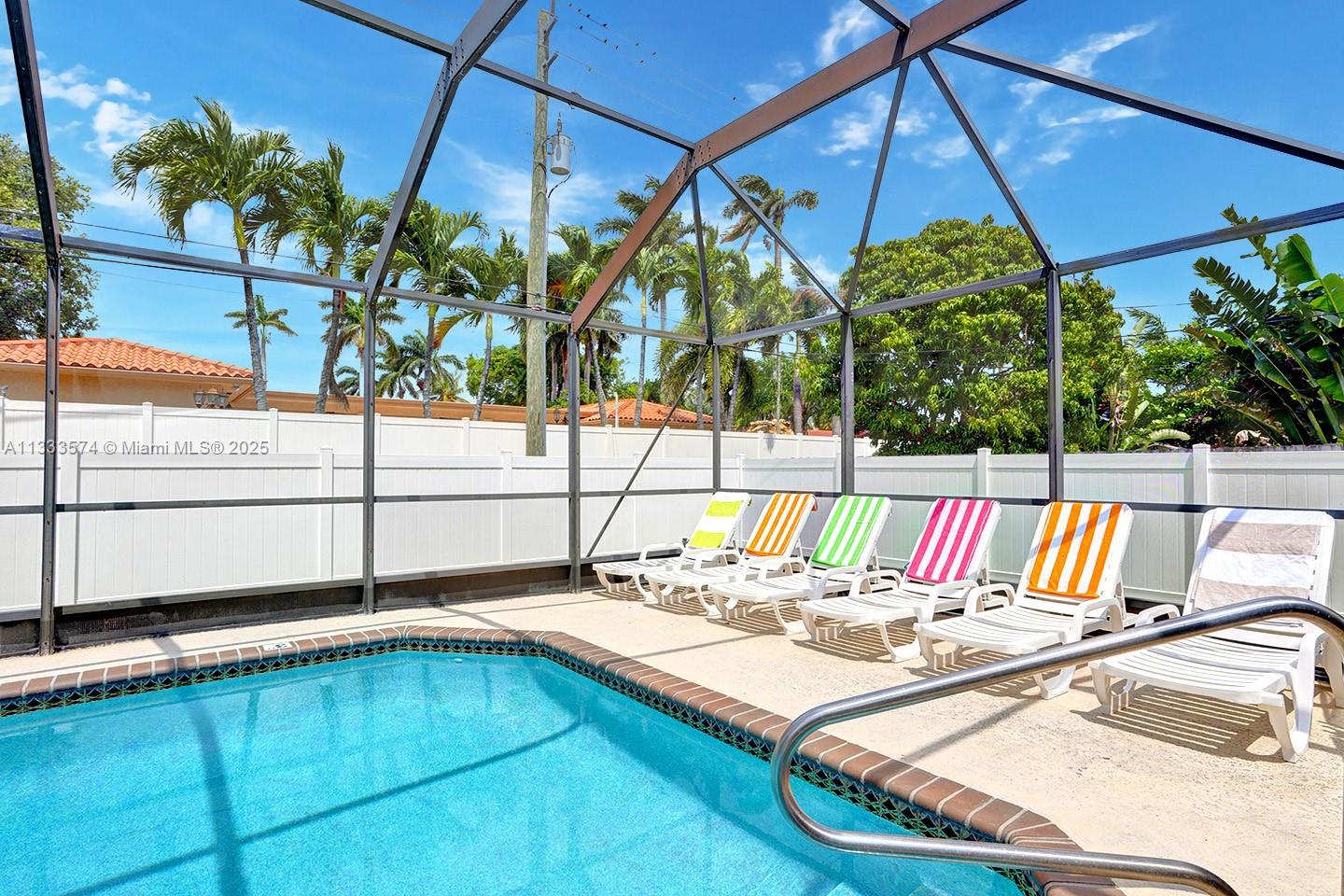 A swimming pool with a screened enclosure and several lounge chairs on a concrete deck — 947 Washington St, Hollywood FL 33019, HOLLYWOOD, FL