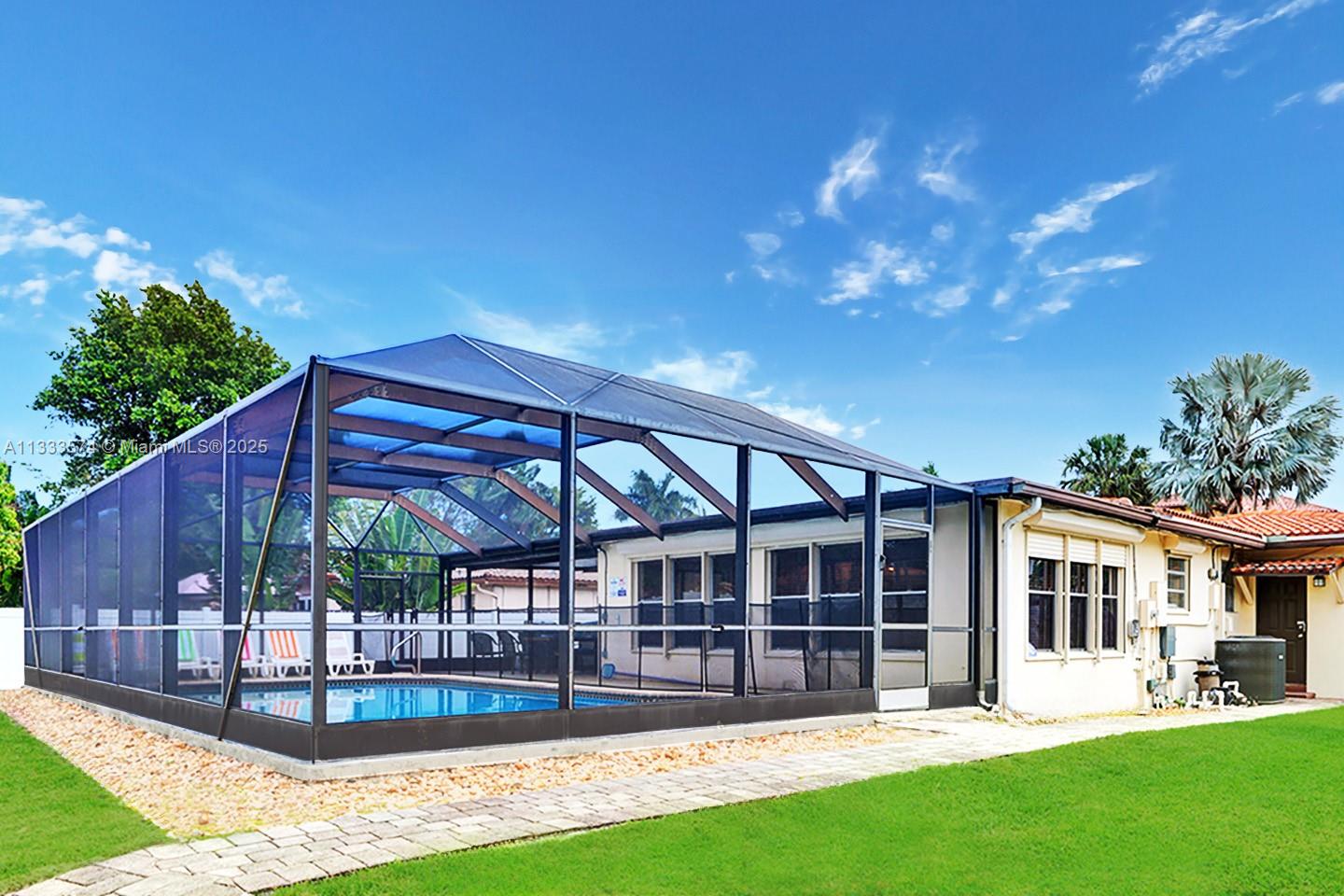 A swimming pool is enclosed by a screened lanai attached to the back of a house — 947 Washington St, Hollywood FL 33019, HOLLYWOOD, FL