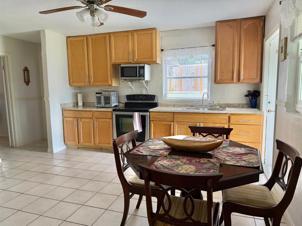 A kitchen with light wood cabinets, tile flooring, and a dining table in the foreground — 7215 JAMES STREET, PORT RICHEY, FL