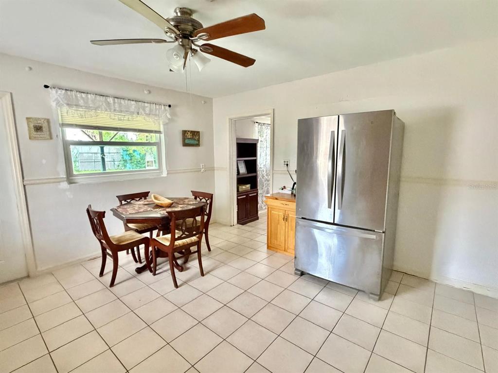 A dining area with tile flooring, a ceiling fan, a table set, and a refrigerator — 7215 JAMES STREET, PORT RICHEY, FL