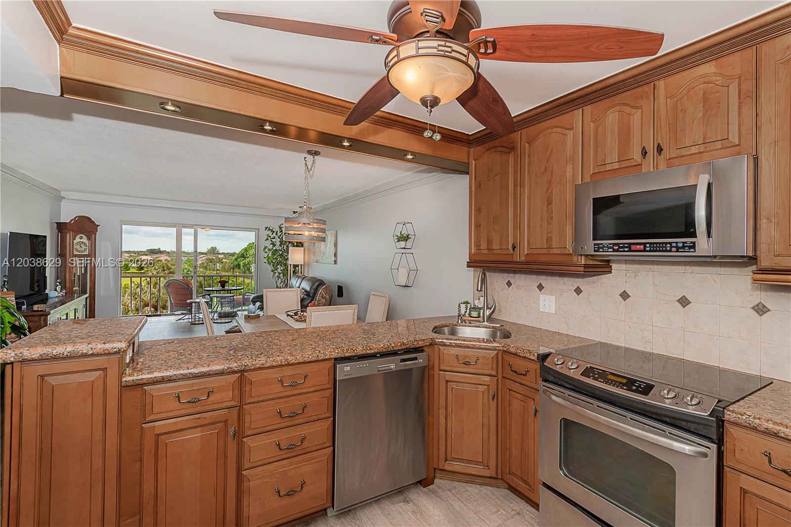 A kitchen with wood cabinets and granite countertops opens to a dining area and balcony — 4800 Hillcrest Ln # 501, Hollywood FL 33021, HOLLYWOOD, FL